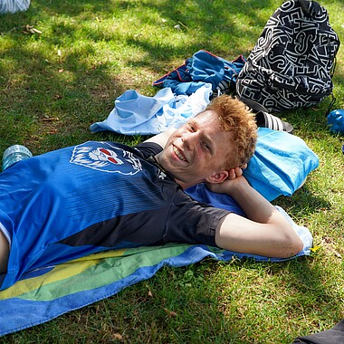 Teilnehmer beim entspannen im Schwimmbad auf der Wiese im Camp Breisach 2026