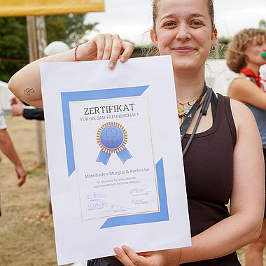 Betreuerin hält Urkunde für eine offizielle Gaufreundschaft zwischen MiMu und Karlsruhe in der Hand im Camp Breisach 2026