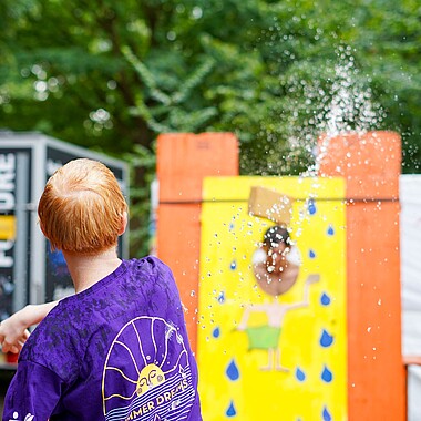 Symbolbild Teilnehmer wirft Betreuer mit Schwamm bei der Betreuerdusche ab beim Tag des offenen Zeltes im Camp Breisach 2026