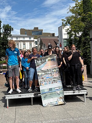 Teilnehmer auf Bühne mit Plakat