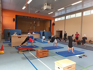 Personen machen in einer Sporthalle Sport
