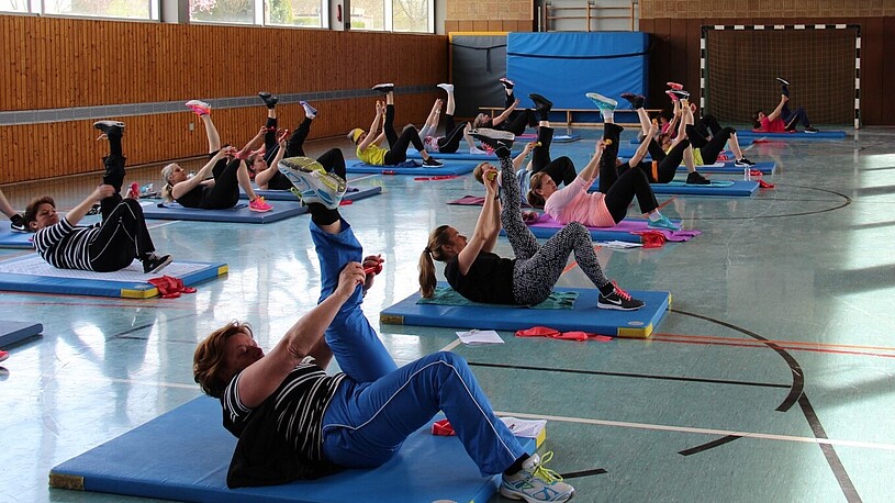 Personen machen in Sporthalle Sport.