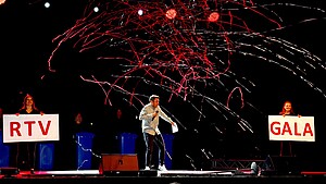 Person steht bei einer Gala mit Mikro auf der Bühne