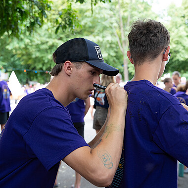 Symbolbild ein Teilnehmer unterschreibt einem anderen Teilnehmer auf dem Rücken im Camp Breisach 2026