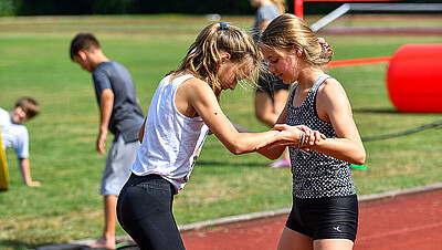 zwei Mädchen unterstützen sich gegenseitig im Schulsport