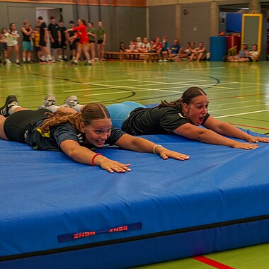Symbolbild Teilnehmerinnen schlittern mit Weichbodenmatten durch die Halle bei Surprise im Camp Breisach 2026