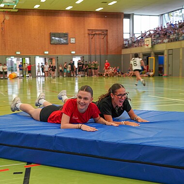Symbolbild Teilnehmerinnen schlittern mit Weichbodenmatten durch die Halle bei Surprise im Camp Breisach 2026