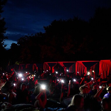 Symbolbild Teilnehmer schwingen ihre Handytaschenlampen während der Lagerfeuerromantik im Camp Breisach 2026