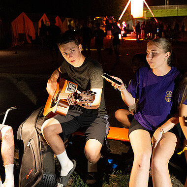 Symbolbild Teilnehmer singen abends am Lagerfeuer im Camp Breisach 2026
