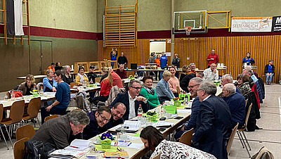 Personen sitzen an Tischen und hören zu