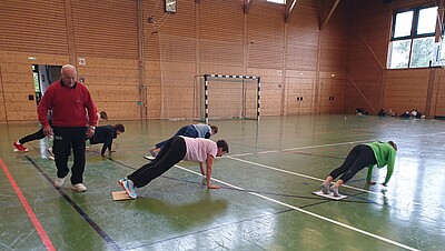 Personen machen in einer Sporthalle Übungen